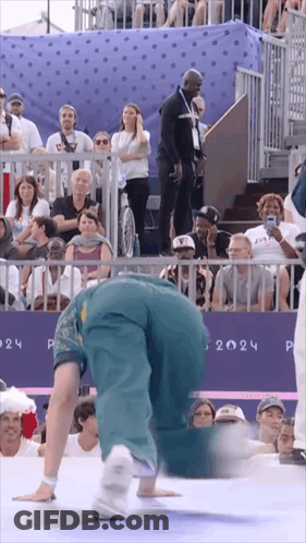 A Person Doing A Handstand In Front Of A Crowd With The Year 2024 On The Wall GIF