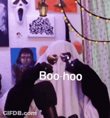 A Person Dressed As A Ghost Is Sitting In Front Of A Microphone And Holding Glasses . GIF