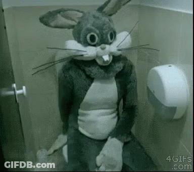 A Person Dressed As Bugs Bunny Is Sitting On A Toilet In A Bathroom . GIF