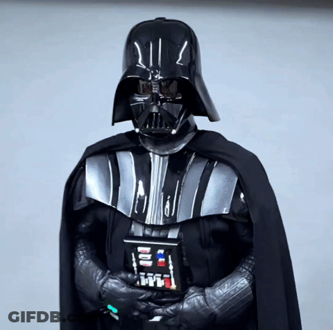 A Person Dressed As Darth Vader Holds A Remote Control In His Hand GIF
