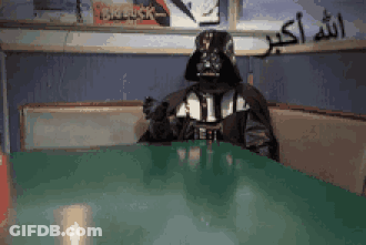 A Person Dressed As Darth Vader Sits At A Table In A Diner GIF