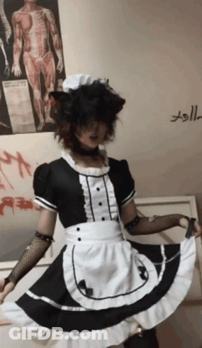A Person Dressed In A Maid Costume Is Standing In Front Of A Wall With A Poster Of A Man 'S Anatomy GIF