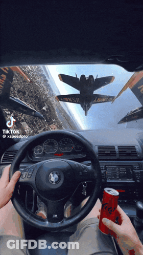 A Person Driving A Car With A Can Of Soda In Front Of Them GIF