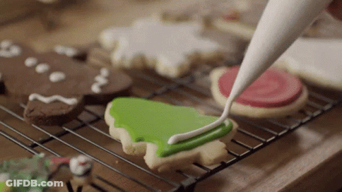 A Person Frosting A Cookie With Green Frosting GIF