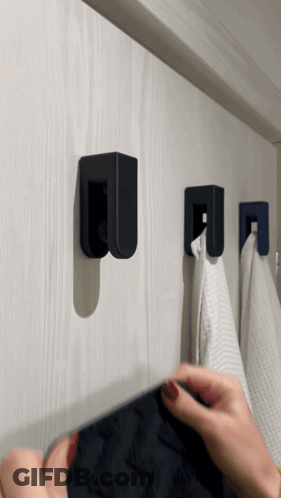 A Person Hangs A Towel On A Hook That Has The Letter U On It GIF