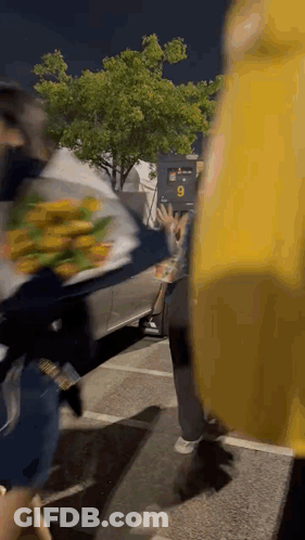 A Person Holding A Bouquet Of Flowers In A Parking Lot . GIF