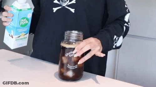 A Person Holding A Carton Of Nut Pods Next To A Jar Of Coffee GIF