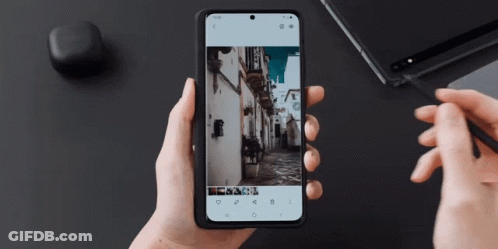 A Person Holding A Cell Phone With A Picture Of A Street On It GIF