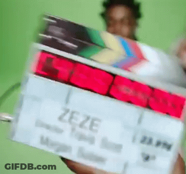 A Person Holding A Clapper Board With The Word Zeze On It GIF