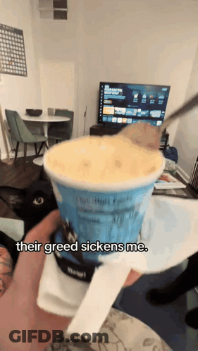 A Person Holding A Cup Of Ice Cream That Says " Their Greed Sickens Me " On It GIF