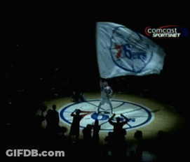 A Person Holding A Flag With A Comcast Logo On The Bottom Right GIF