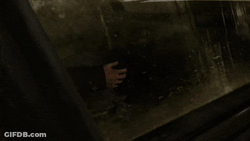 A Person Holding A Gun In A Dark Room With A Blurred Background GIF