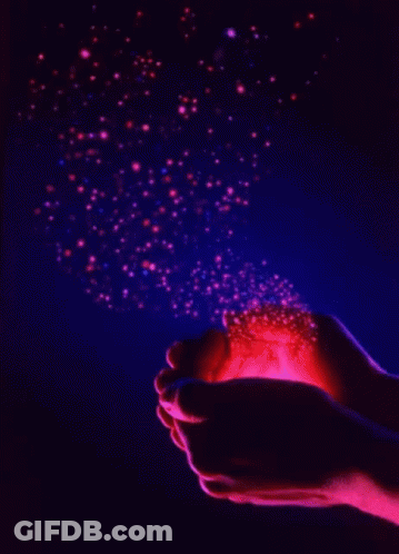 A Person Holding A Light In Their Hands With Sparkles Coming Out Of It GIF