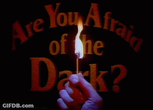 A Person Holding A Lit Match In Front Of A Sign That Says Are You Afraid Of The Dark GIF