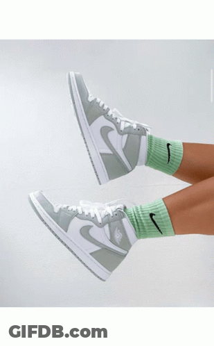 A Person Holding A Pair Of Green And White Nike Sneakers GIF