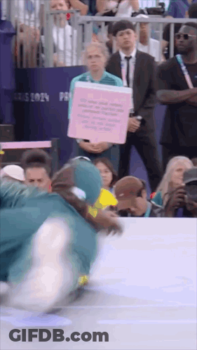 A Person Holding A Pink Sign That Says ' Paris 2024 ' On It GIF