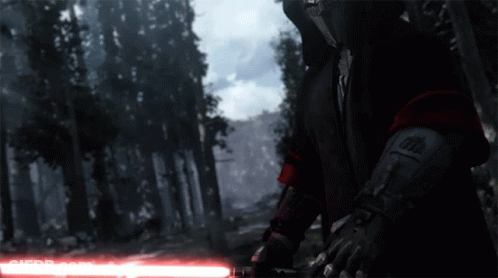 A Person Holding A Red Lightsaber In A Forest GIF