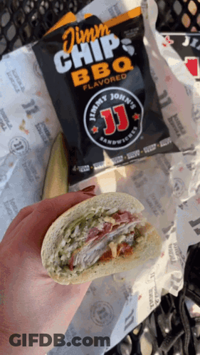 A Person Holding A Sandwich Next To A Bag Of Jimmy John 'S Bbq Chips GIF