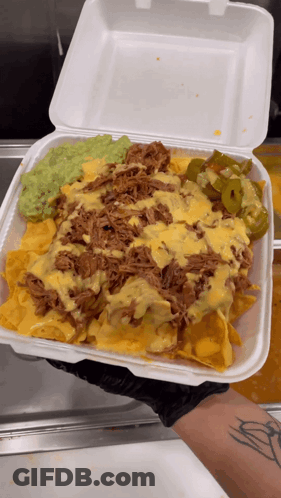 A Person Holding A Styrofoam Container Filled With Nachos Guacamole And Cheese GIF