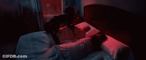 A Person Holding A Sword In Front Of A Window With A Blue Curtain GIF