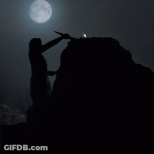 A Person Holding A Torch On Top Of A Rocky Hill With A Full Moon In The Background GIF