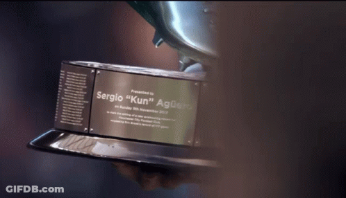 A Person Holding A Trophy That Says Sergio " Kun " On It GIF