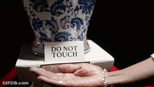 A Person Holding A Vase With A Do Not Touch Sign On It GIF