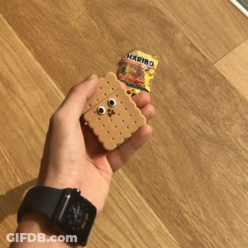 A Person Holding An Airpod Case In The Shape Of A Cookie Next To A Haribo Bag GIF