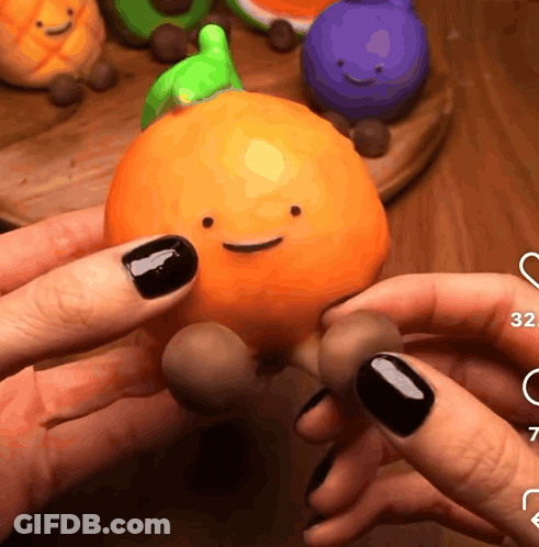 A Person Holding An Orange With A Face On It GIF