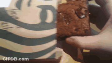 A Person Holds A Brownie In Front Of A Starbucks Logo GIF