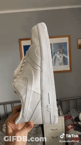 A Person Holds A Pair Of White Nike Air Force 1 Sneakers GIF