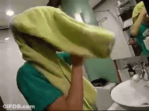 A Person In A Bathroom With A Yellow Towel On Their Head GIF