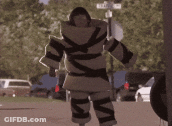 A Person In A Black And White Striped Coat Is Standing In Front Of Trees GIF