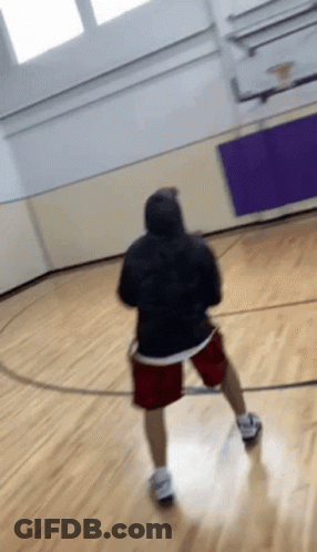 A Person In A Black Hoodie And Red Shorts Is Playing Basketball On A Court GIF