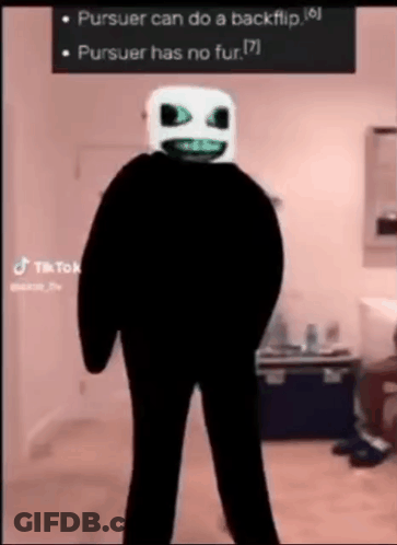 A Person In A Black Suit With A White Mask On Their Face . GIF