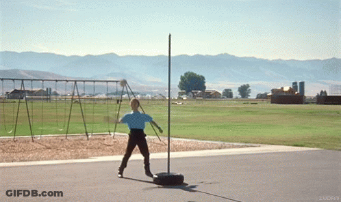 A Person In A Blue Shirt Is Throwing A Frisbee In A Field With Mountains In The Background GIF