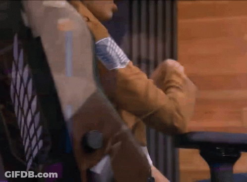 A Person In A Brown Jacket Is Sitting In A Chair With Their Arms Crossed . GIF