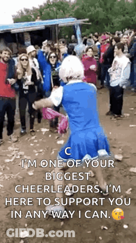 A Person In A Cheerleader Costume Is Dancing In Front Of A Crowd Of People . GIF