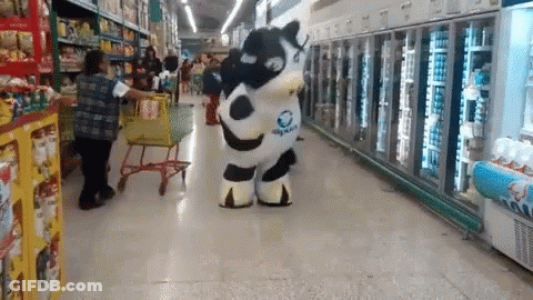 A Person In A Cow Costume Is Walking Down A Grocery Store Aisle GIF