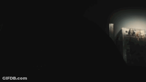 A Person In A Dark Room With A Light Shining On Their Face GIF