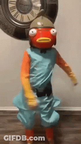 A Person In A Fish Costume Is Dancing In Front Of A Large Clock . GIF