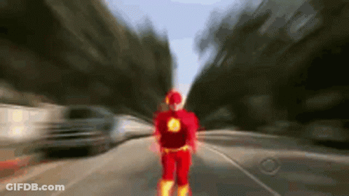 A Person In A Flash Costume Is Walking Down A Street . GIF