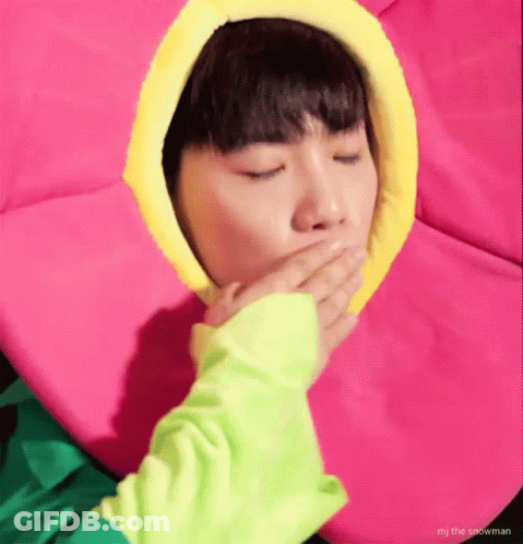 A Person In A Flower Costume Is Covering Their Mouth With Their Hand . GIF