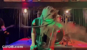 A Person In A Green Costume Is Standing In A Dark Room . GIF