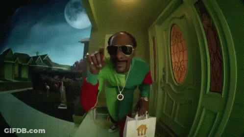 A Person In A Green Jacket Is Standing In Front Of A Door With A Bag In Front Of It GIF