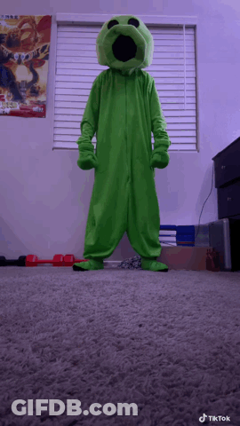 A Person In A Green Monster Costume Stands In Front Of A Window With A Poster On It GIF