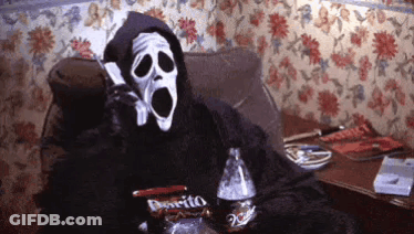 A Person In A Grim Reaper Costume Is Sitting On A Couch Talking On A Cell Phone GIF