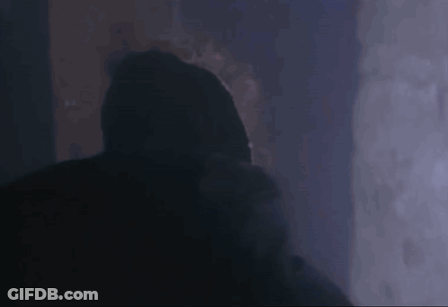A Person In A Hooded Jacket Is Standing In The Dark . GIF