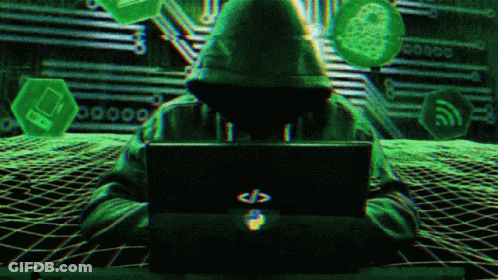 A Person In A Hoodie Is Sitting In Front Of A Laptop Computer GIF