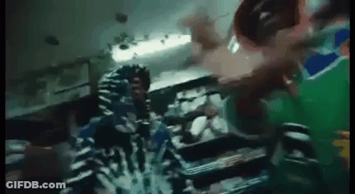A Person In A Hoodie Is Standing In A Dark Room With A Green Background . GIF